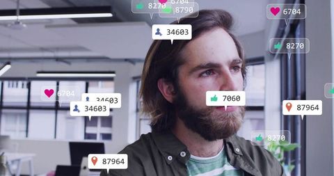 Gazing bearded man in modern open-plan office with social media notification overlays