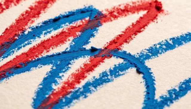 Overlapping red and blue crayon strokes on textured paper, macro pastel granulation abstract
