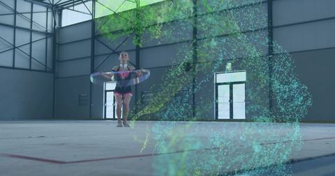 Young gymnast twirling hoop with vibrant holographic motion trail in modern indoor gymnasium