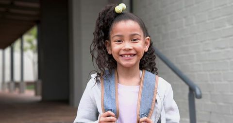 Smiling preteen student with backpack on school walkway