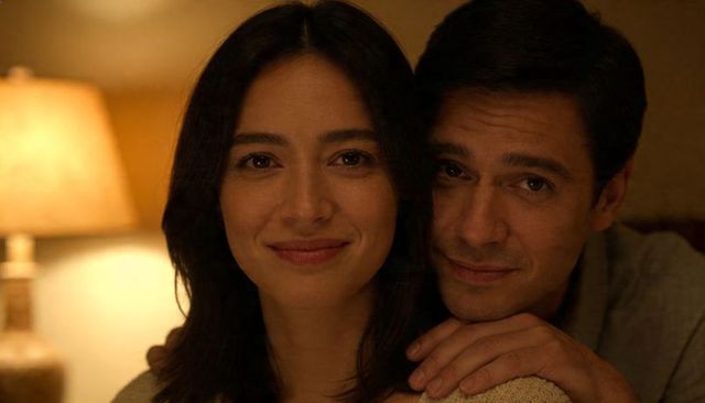 Couple sharing warm intimate moment with hands on shoulders and soft lamp glow