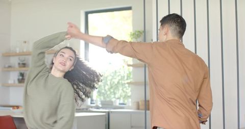 Couple Enjoying Playful Spin in Cozy Kitchen Setting