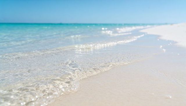 Glistening turquoise sea lapping white sand beach with gentle crystal clear waves