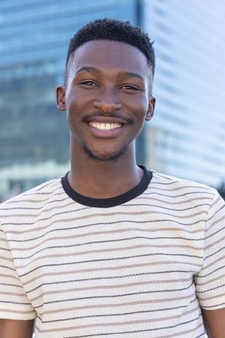 Smiling african man facing camera in urban tech district wearing striped tee