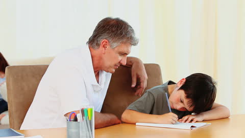 Father Observing Son Doing Homework at Home