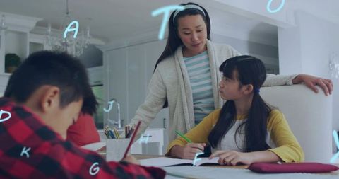 Mother guiding daughter with homework at modern kitchen table, supporting home learning