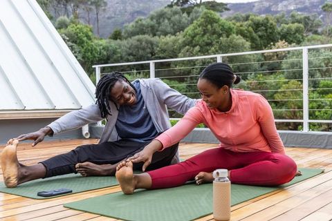 African american couple stretching on rooftop yoga mats for outdoor fitness and wellness