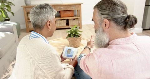 Senior couple checking blood pressure in cozy living room