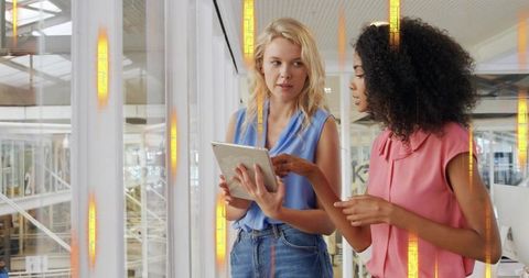 Colleagues collaborating over tablet in bright glass office atrium