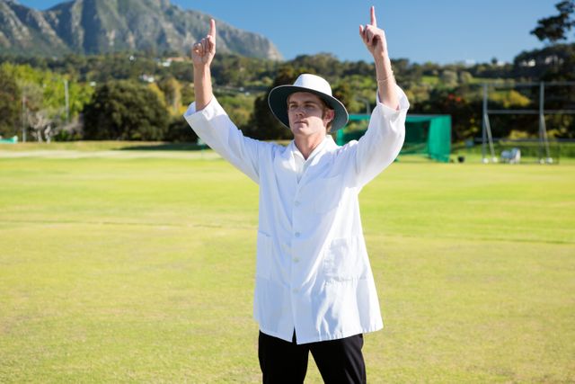 Low angle view of cricket umpire signalling six at match during sunny day