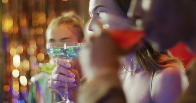 Image of caucasian woman drinking cocktail standing at a bar with diverse friends. Friendship, going out, drinking and socialising concept.