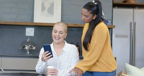 Diverse colleagues checking smartphone in modern office kitchen during break