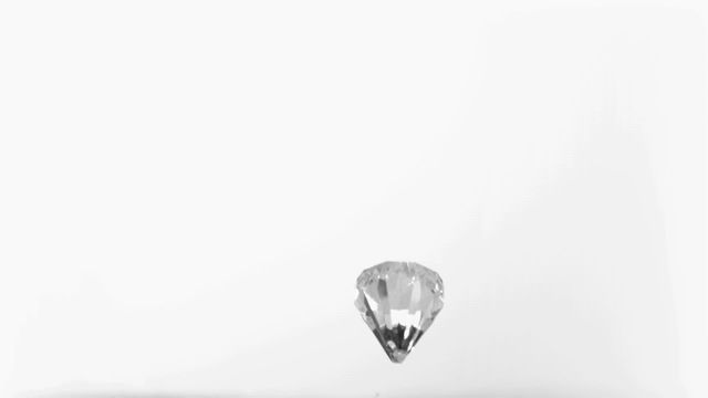 A clear diamond captured in super slow motion falling against a white background, showcasing its brilliance and clarity. The minimalistic and elegant composition highlights the diamond's sparkling facets, perfect for use in jewelry advertisements, luxury branding, or illustrations about wealth and elegance.