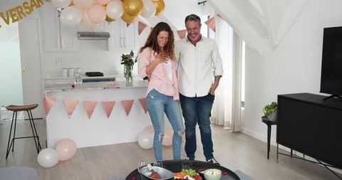 Happy couple celebrating anniversary at home with surprise