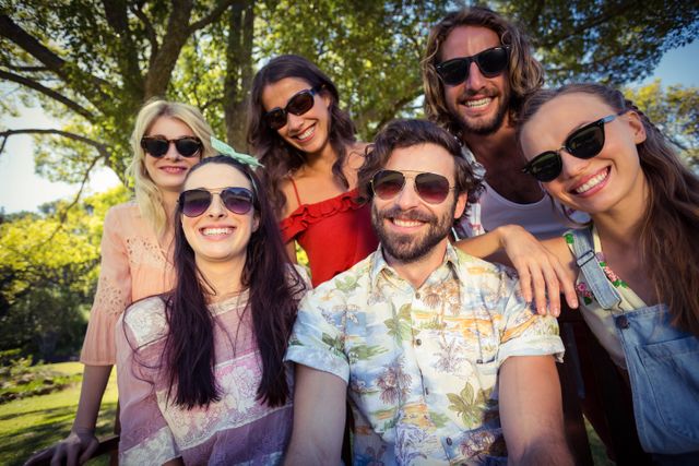 Group of friends enjoying a sunny day in the park, wearing casual summer clothes and sunglasses. Perfect for use in advertisements, social media posts, and articles about friendship, outdoor activities, and summer fun.