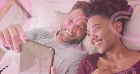Happy Diverse Couple Enjoying Time Together on Tablet in Bedroom