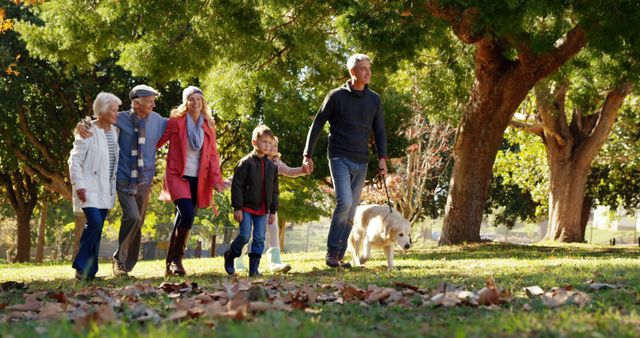 Multigenerational family with grandparents, parents, and children walking together in a park while walking a dog. Ideal for concepts related to family bonding, outdoor activities, health and wellness, diverse families, and autumn leisure activities.