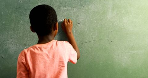 Young boy writing on chalkboard capturing learning moment