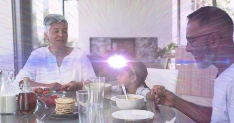 Sharing sunny family breakfast at modern glass table with pancakes and sunlight rays