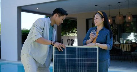 Couple installing solar panel at poolside enjoying sustainable modern patio living