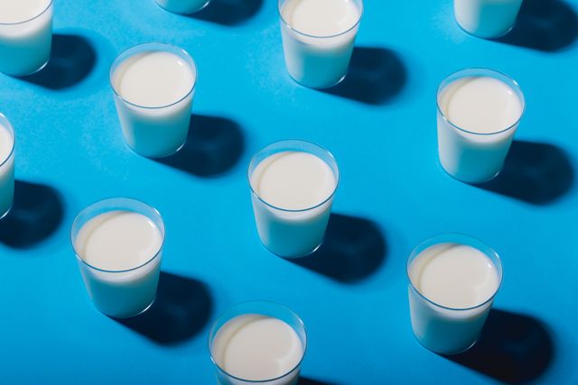 High angle view of milk glasses arranged over blue background with copy space. unaltered, food, drink, studio shot and healthy eating.