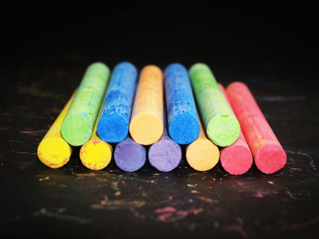 Brightly colored chalk sticks arranged neatly on black background. Ideal for educational materials, art projects, school supply advertisements, and creativity-promoting visuals.