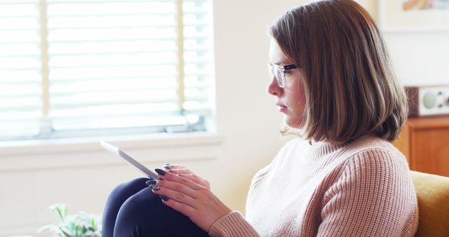 Young Woman Reading on Digital Tablet by Window in Bright Room - Download Free Stock Images Pikwizard.com