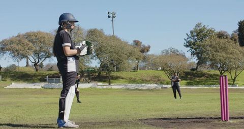 Female Cricket Player Preparing to Bat on Sunny Day
