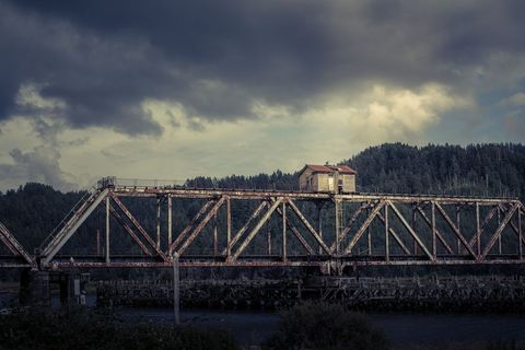 Rustic iron bridge under darkening sky in nature