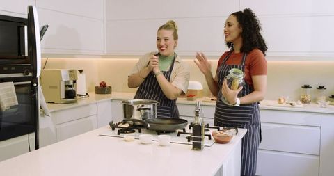 Female Friends Cooking Together in Modern Kitchen With Joyful Expressions