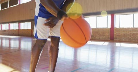 Energetic Athlete Dribbling Basketball in School Gymnasium