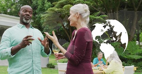 Mature couple chatting and holding wine at backyard garden party with world map overlay