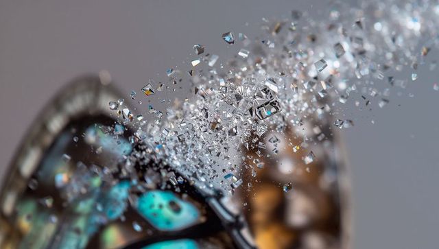 Butterfly wing fragment erupting into crystalline shards, iridescent macro motion surge