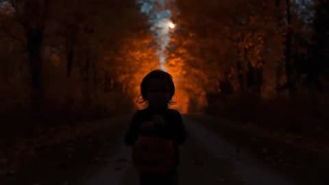 Silhouette of Child with Pumpkin Bucket on Enchanting Autumn Path