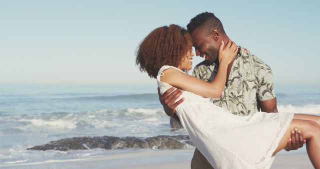 This image shows a joyful couple embracing on a beach with the ocean in the background. It can be used for romance-themed projects, travel advertisements, and lifestyle blogs.