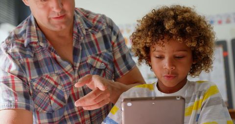 Male Teacher Guiding Young Schoolboy on Digital Tablet Use in Classroom - Download Free Stock Images Pikwizard.com