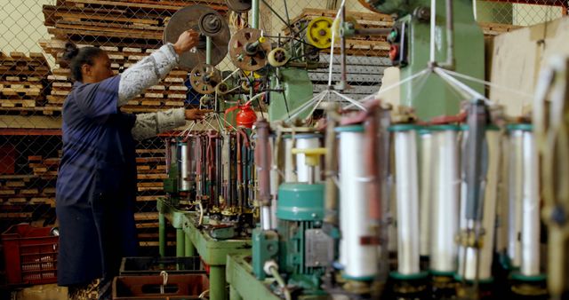 A worker, Asian, operates machinery for textile production in an industrial setting, with copy space. Their focus on the task showcases the intricate work involved in fabric manufacturing.