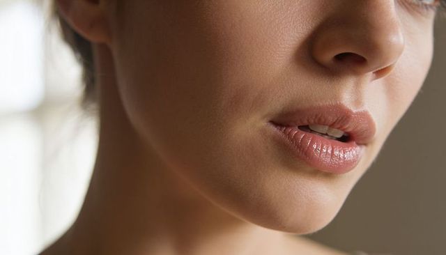 Closeup glossy lips and defined jawline portrait showing smooth skin in soft window light