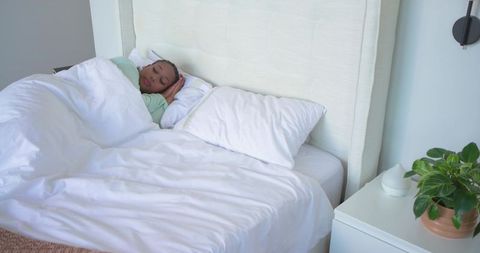 African american woman sleeping peacefully on white bed in minimalist neutral bedroom