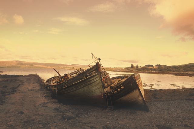 Classic shipwreck scene on a quiet beach at sunset. Useful for themes of abandonment, nostalgia, nature's beauty, and historical maritime settings. Ideal for travel blogs, historical articles, and artwork reflecting serene nature.