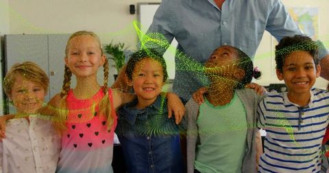 Diverse elementary students linking arms and smiling in classroom with teacher support
