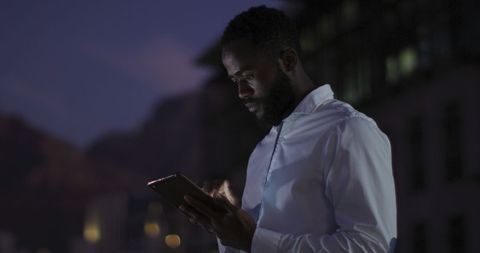 Thoughtful Businessman Using Tablet on Night Office Terrace