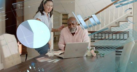 Black man and asian partner reviewing finances on laptop at home with digital data charts
