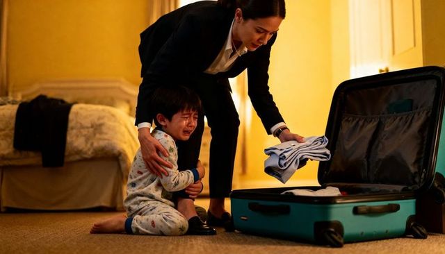 Soothing caregiver holding crying child while packing suitcase in bedroom