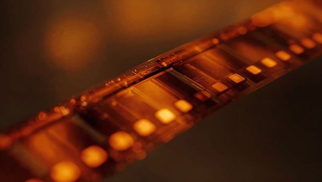 Amber-tinted film strip under darkroom light with exposed frames