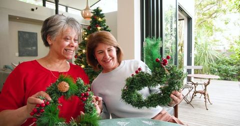 Mother and daughter crafting festive wreaths at home