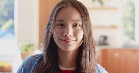 Cheerful Young Asian Woman Smiling in Cozy Kitchen