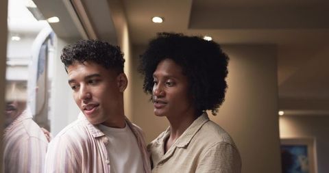 Leaning couple sharing quiet moment in warm hallway with reflection and soft lighting