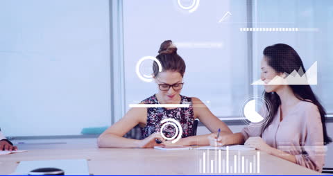 Women Collaborating at Office Desk with Data Analytics Overlay