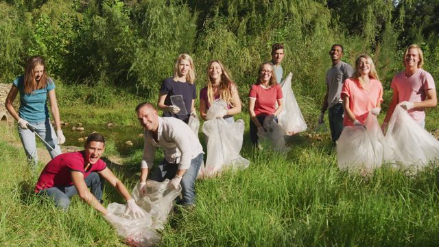 A cheerful group of diverse volunteers cleaning up a river in a rural area on a sunny day. They are collecting rubbish in large plastic bags, demonstrating teamwork and environmental care. Perfect for themes related to community service, environmental conservation, social responsibility, and outdoor activities.